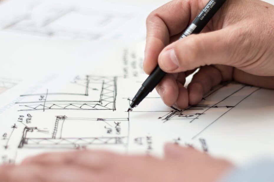 Close-up of hand drawing intricate technical designs on blueprint with pen, ideal for engineering or architecture themes.